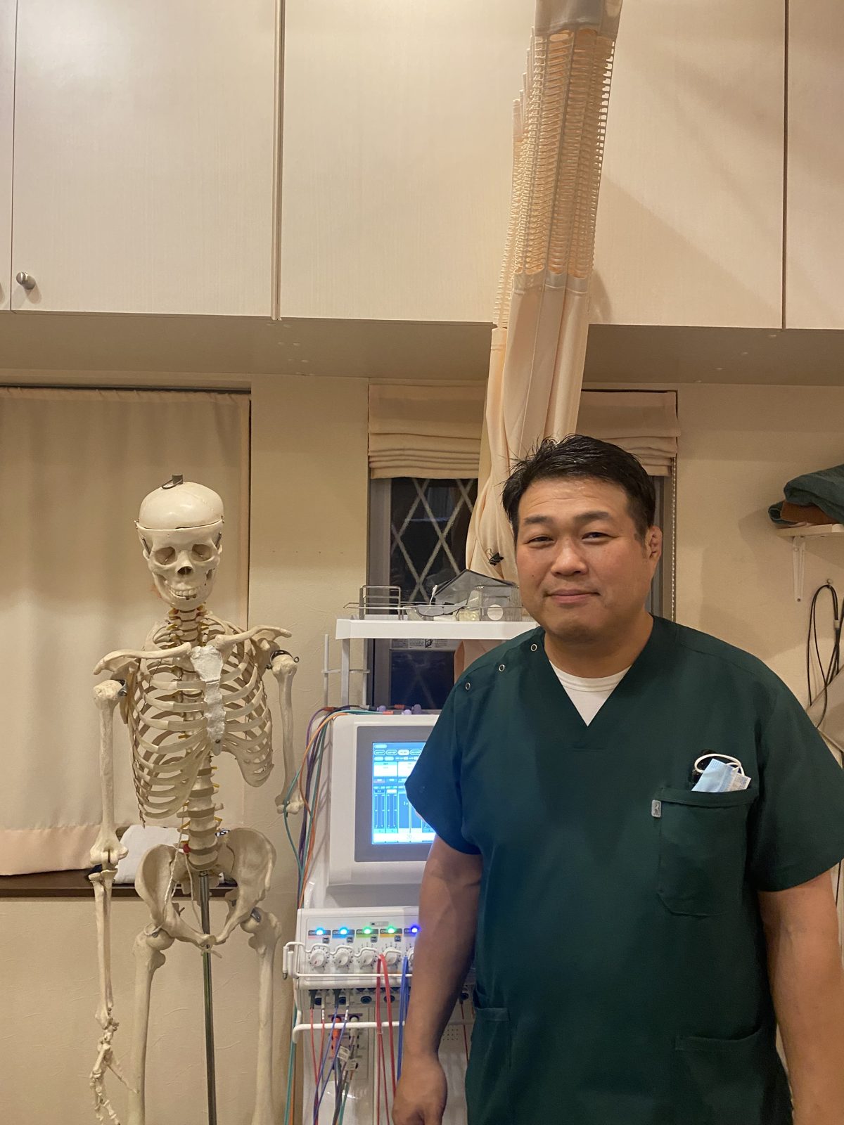 骨格模型とともに体のしくみを説明する院長